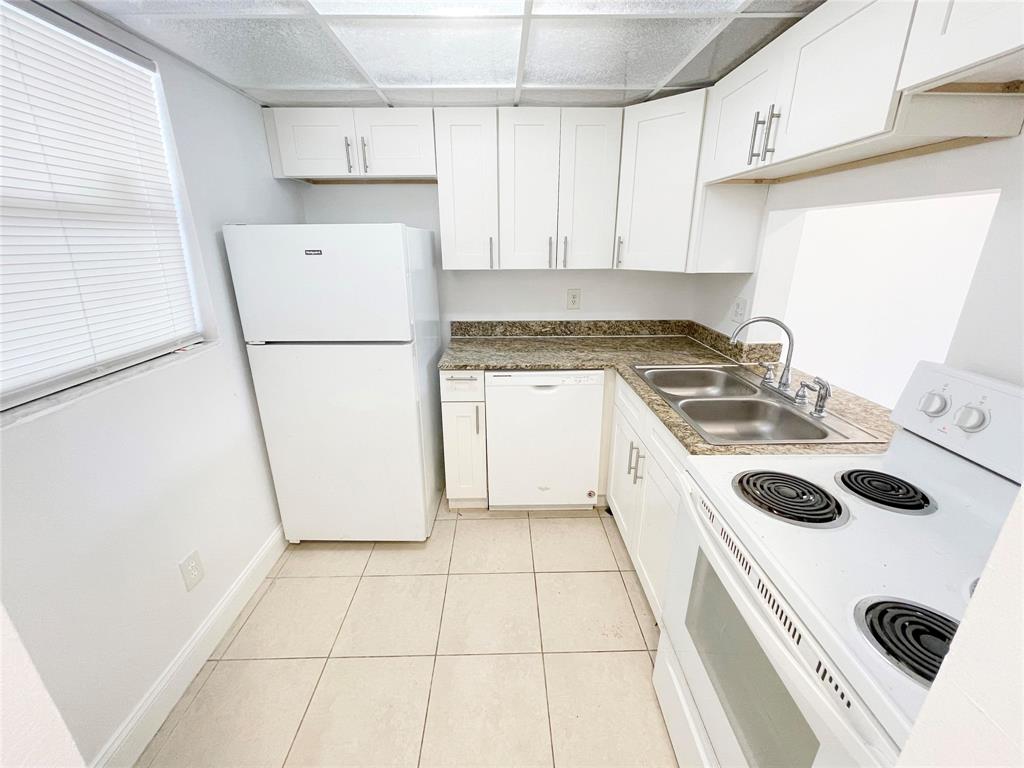 a kitchen with a sink a refrigerator and white cabinets
