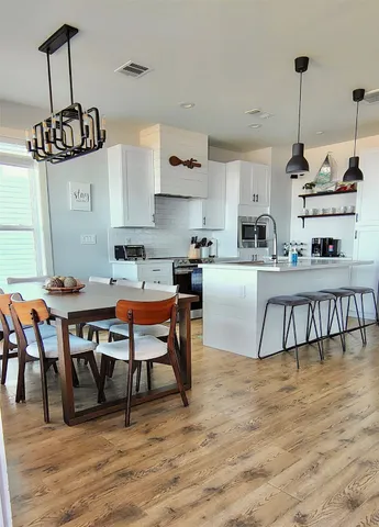 a kitchen with stainless steel appliances granite countertop a dining table chairs stove a refrigerator and cabinets