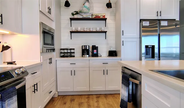 a kitchen with white cabinets and appliances
