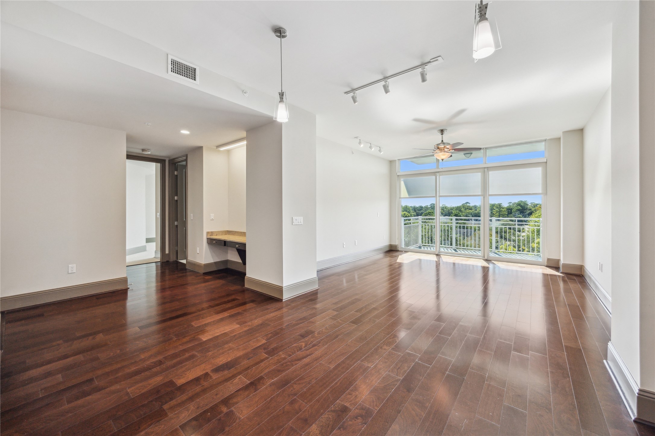 a view of empty room with wooden floor and fan