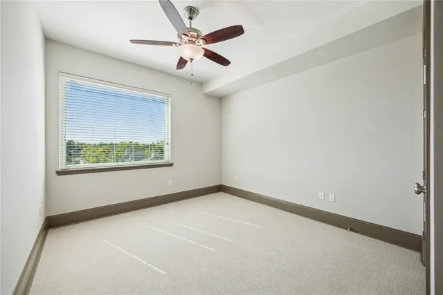 an empty room with a window and a ceiling fan