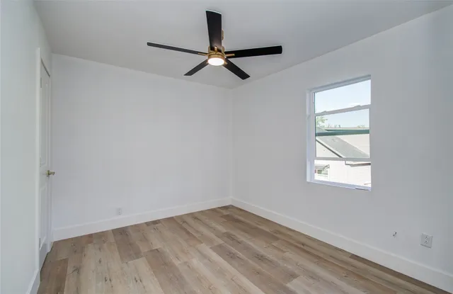 an empty room with a window and a ceiling fan