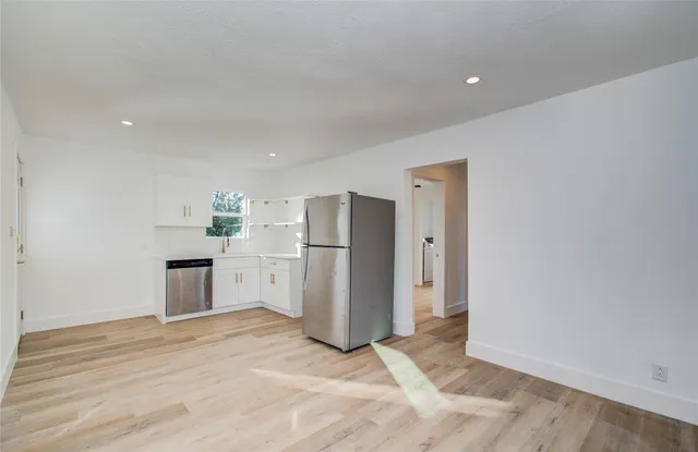 a view of a kitchen with refrigerator and white cabinets