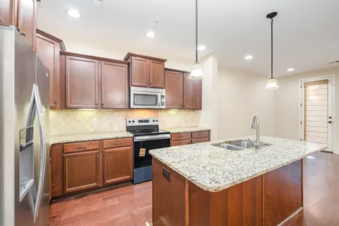 a kitchen with kitchen island granite countertop a sink stove and refrigerator