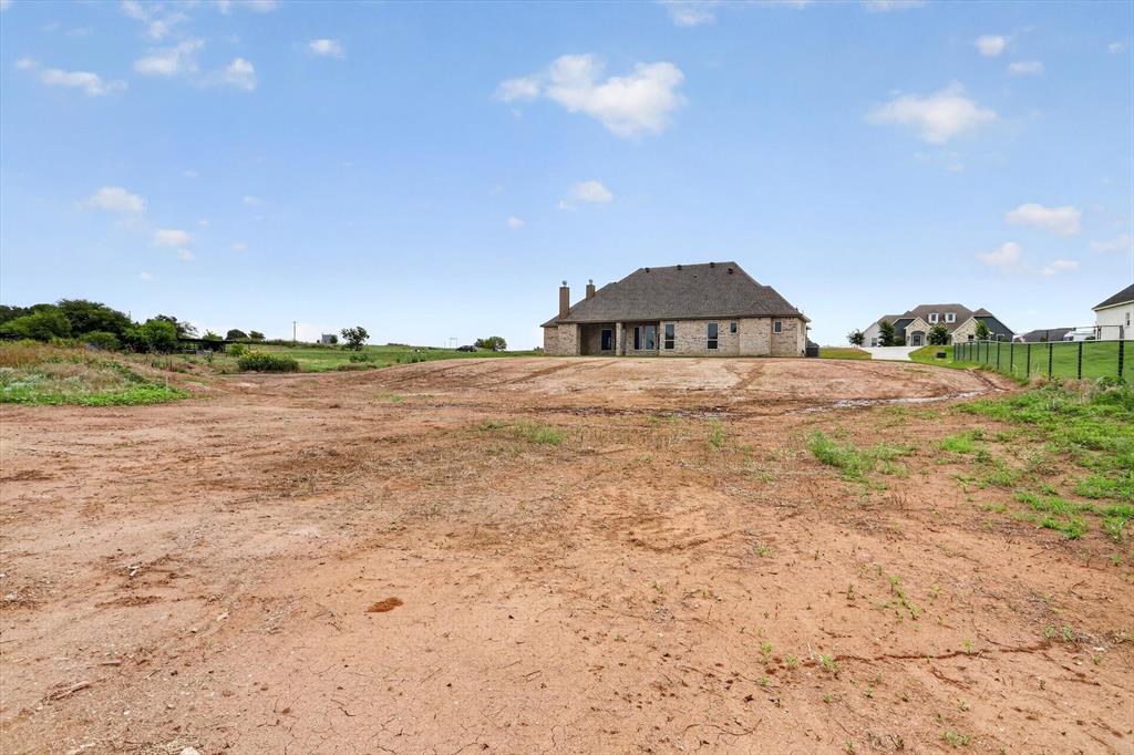 471 Red Bird Drive Springtown, TX 76082 - Photo 34 of 35 Large undeveloped lot featuring exposed earth, distant residential structures, and a partial perimeter fence