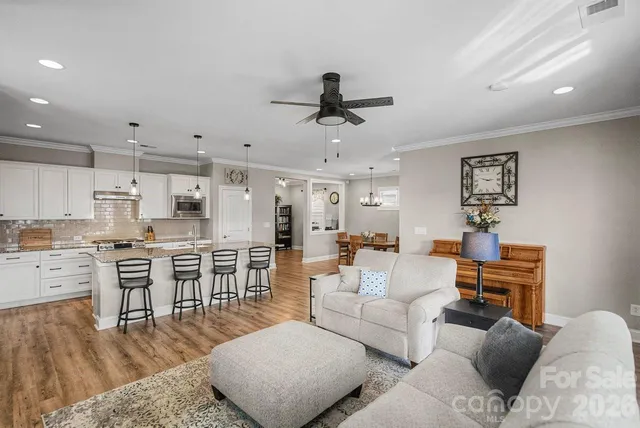 a living room with furniture kitchen view and a wooden floor