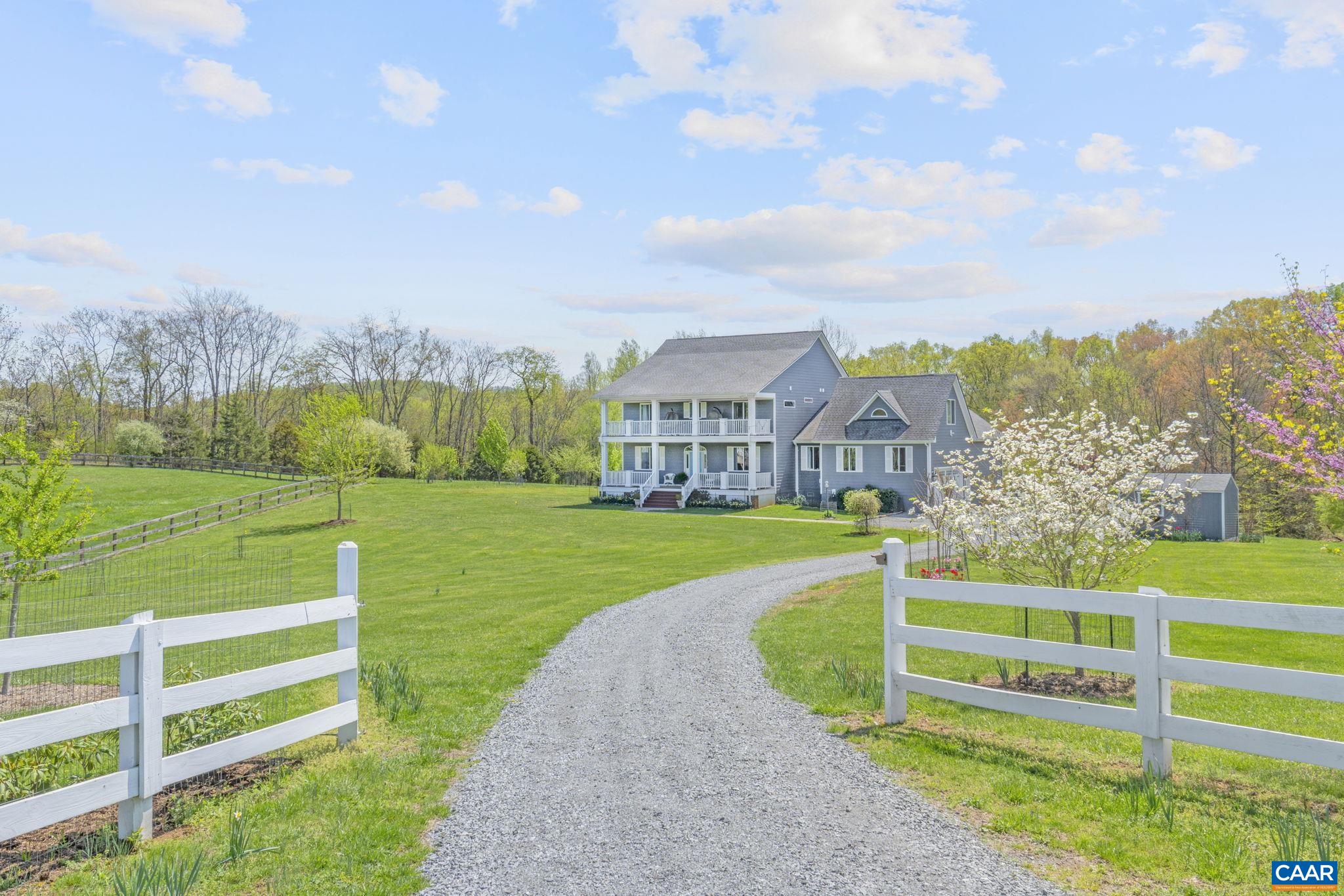 a view of a house with a big yard and a large trees
