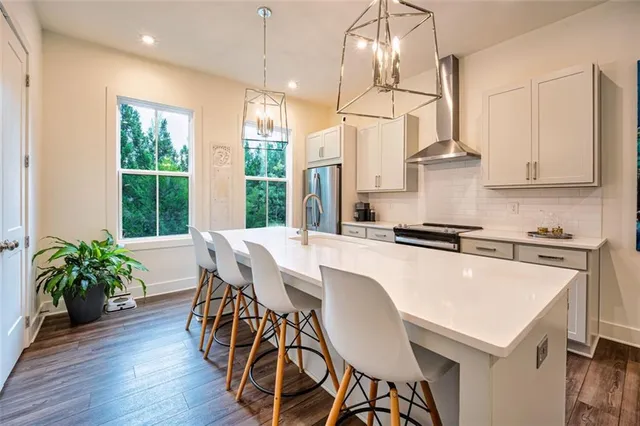 a kitchen with stainless steel appliances granite countertop a stove a refrigerator a sink a dining table and chairs with wooden floor