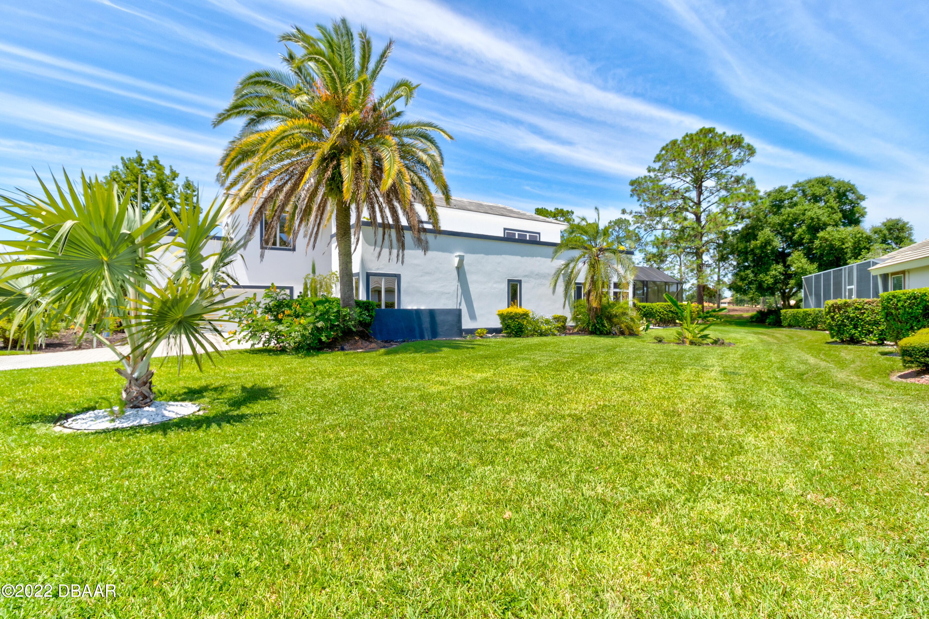 13 Bay Pointe Drive Ormond Beach, FL 32174 - Photo 35 of 44 a white house with a big yard and palm trees