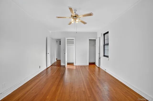 a view of an empty room with window and wooden floor