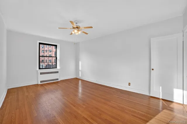 a view of an empty room with window and wooden floor