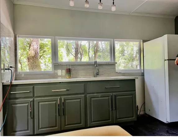 a kitchen with stainless steel appliances a sink dishwasher a refrigerator and cabinets