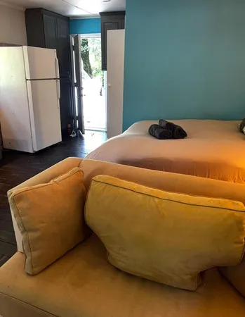 a bed sitting in a kitchen and a refrigerator