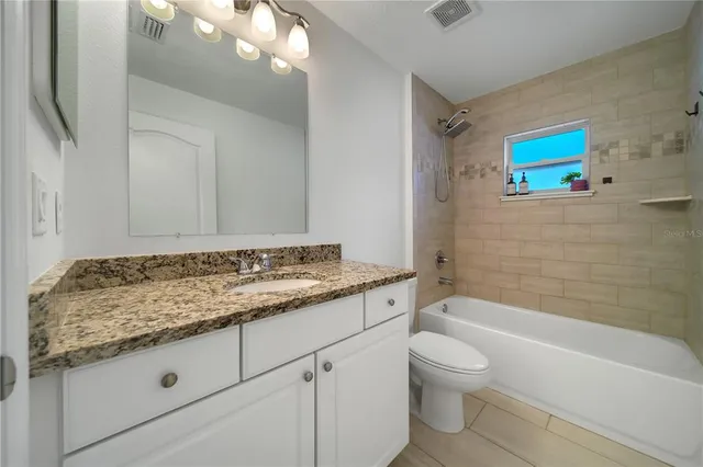 a bathroom with a granite countertop sink a toilet and bathtub