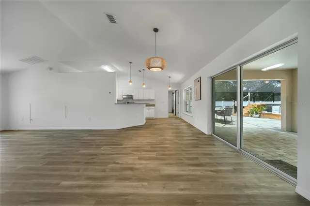 a view of a room with wooden floor a ceiling fan and window