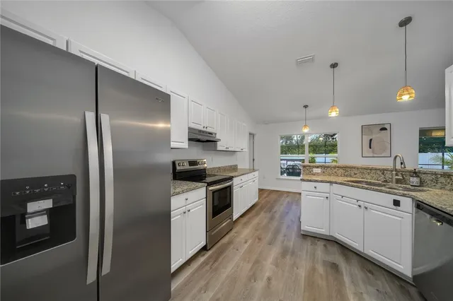 a kitchen with stainless steel appliances granite countertop a stove a sink and a refrigerator