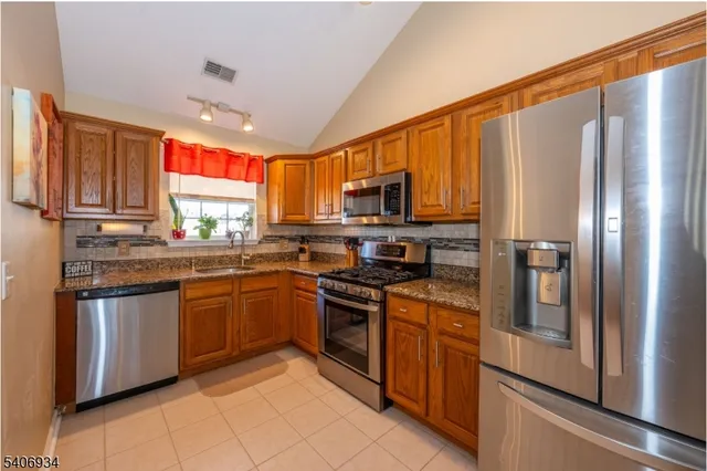a kitchen with stainless steel appliances granite countertop a refrigerator stove top oven and sink