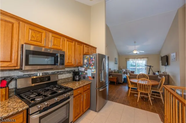 a kitchen with stainless steel appliances granite countertop a stove top oven a sink a dining table and chairs with wooden floor