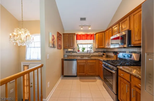 a kitchen with stainless steel appliances granite countertop a stove top oven a sink a dining table and chairs with wooden floor