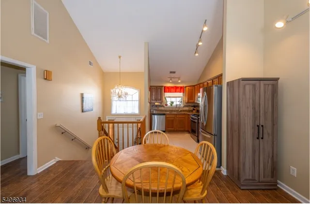 a kitchen with stainless steel appliances kitchen island granite countertop a refrigerator a stove a sink a dining table and chairs with wooden floor