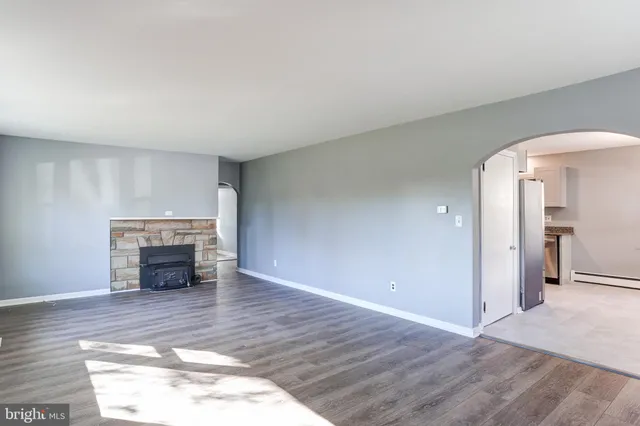 an empty room with wooden floor fireplace and windows