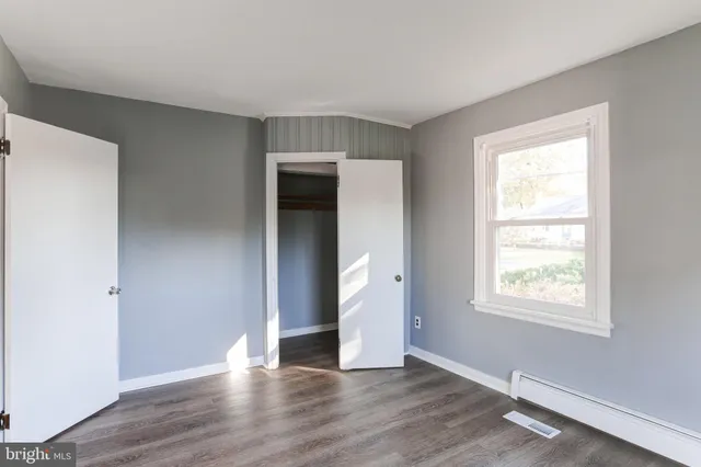 an empty room with wooden floor closet and windows