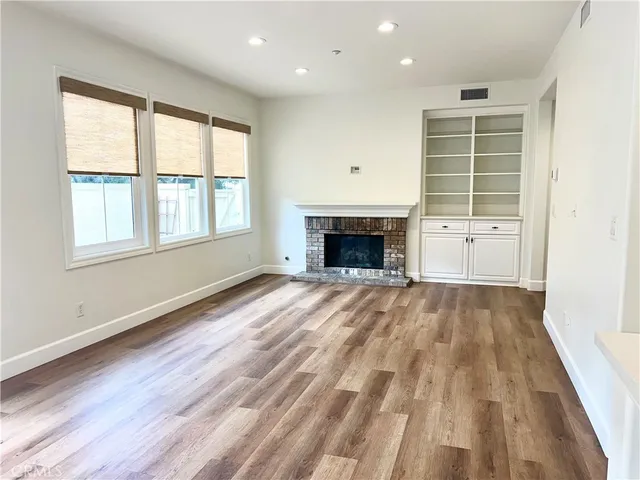 an empty room with wooden floor a fireplace and windows