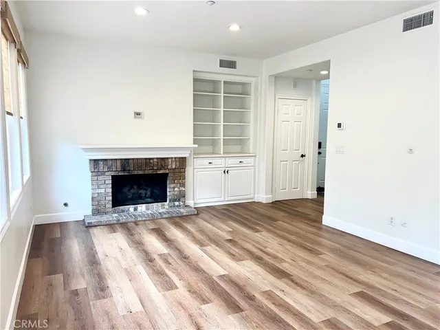 an empty room with wooden floor a fireplace and windows