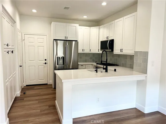 a view of a kitchen with kitchen island white cabinets and stainless steel appliances