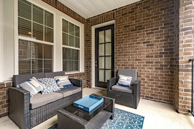 a view of a patio with couches chairs potted plants and wooden floor