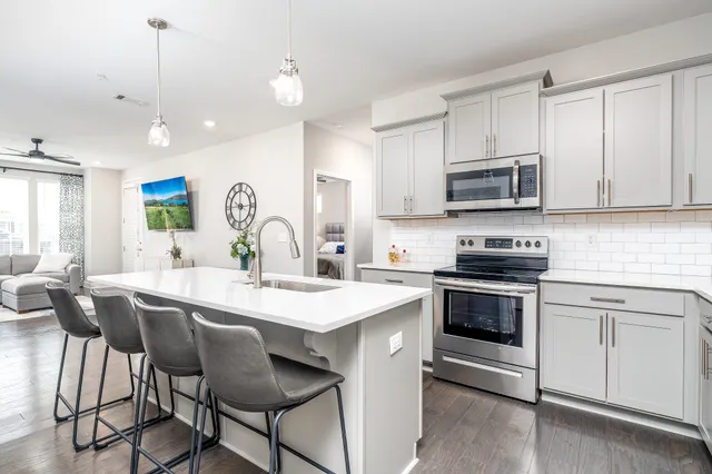 a kitchen with stainless steel appliances a stove a sink a microwave a center island and cabinets