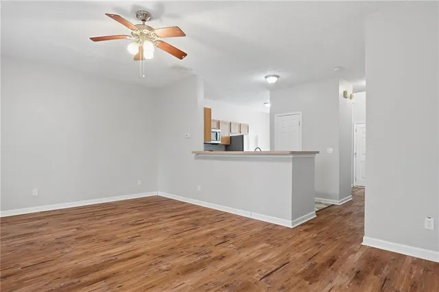 an empty room with wooden floor and a ceiling fan