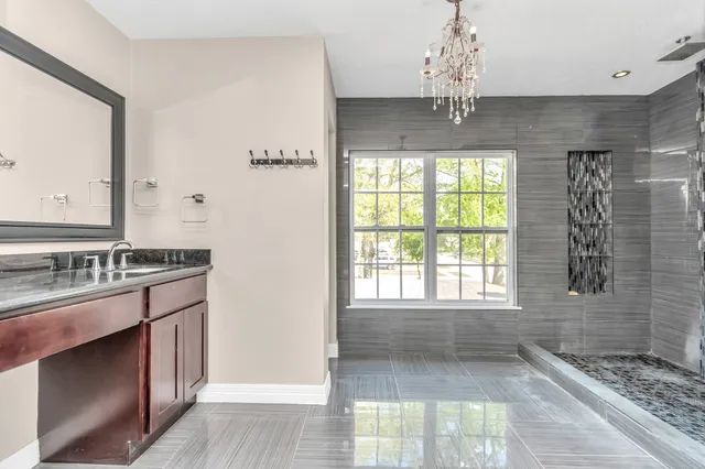 a bathroom with a granite countertop sink a large mirror and a shower