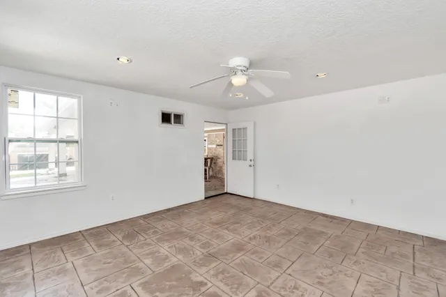 an empty room with windows and ceiling fan