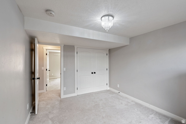 444 South Saddle Road Grantsville, UT 84029 - Photo 19 of 33 Unfurnished bedroom with a closet, light colored carpet, and a textured ceiling
