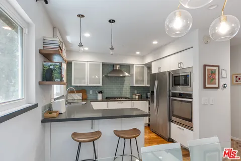 a kitchen with stainless steel appliances granite countertop a sink refrigerator and microwave