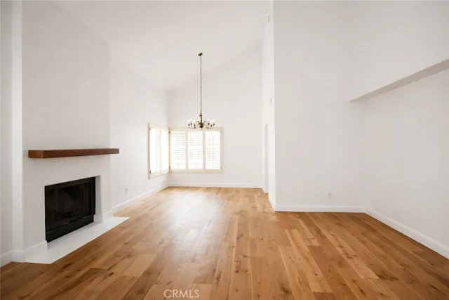 a view of empty room with wooden floor and fireplace