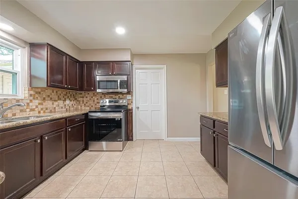 a kitchen with granite countertop a refrigerator and a sink