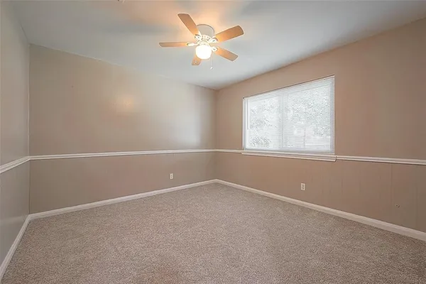 an empty room with a window and a fan