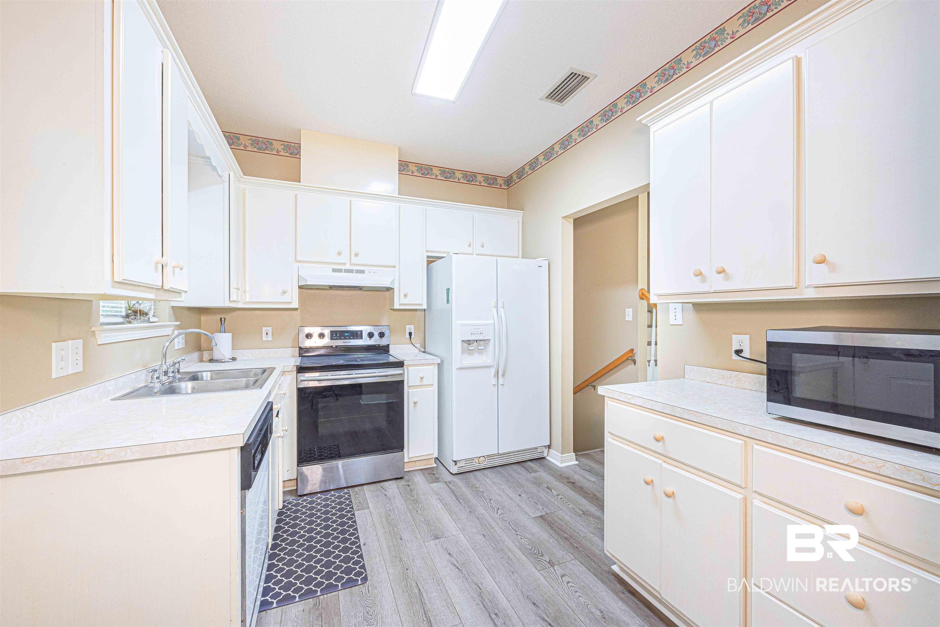 175 Montclair Loop Daphne, AL 36526 - Photo 10 of 44 Kitchen with appliances with stainless steel finishes, light wood-type flooring, light countertops, and white cabinetry