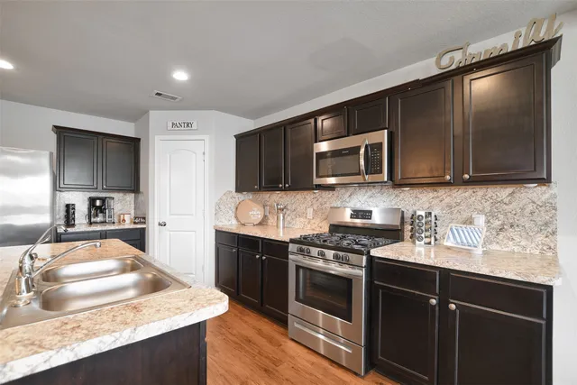 a kitchen with stainless steel appliances granite countertop a stove microwave and sink
