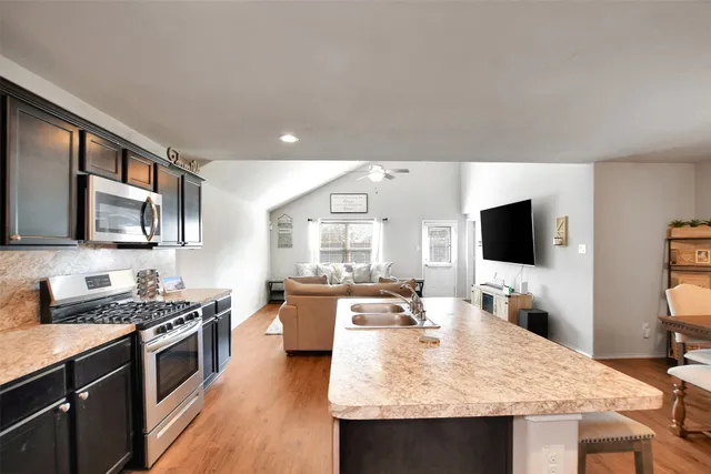 a large kitchen with a stove and a flat screen tv