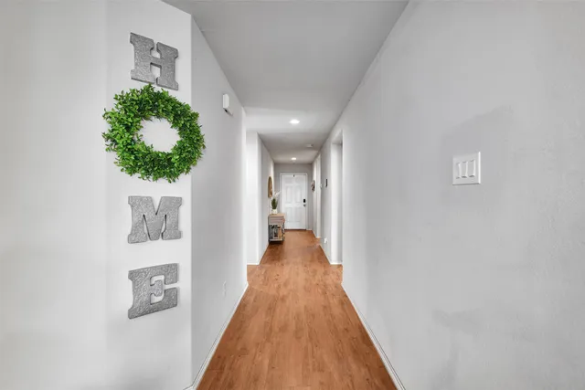 a view of a hallway with wooden floor and a potted plant