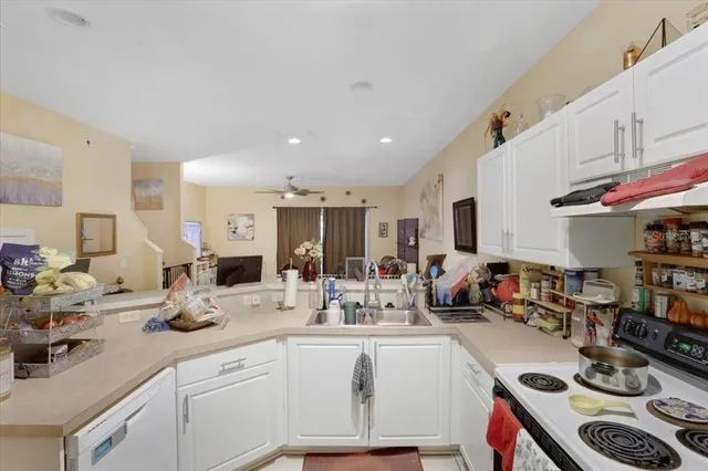 a kitchen with stainless steel appliances kitchen island granite countertop a sink dishwasher stove and white cabinets with wooden floor