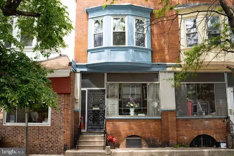 a view of a brick house with windows and plants