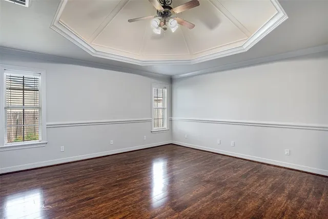 an empty room with wooden floor fan and windows