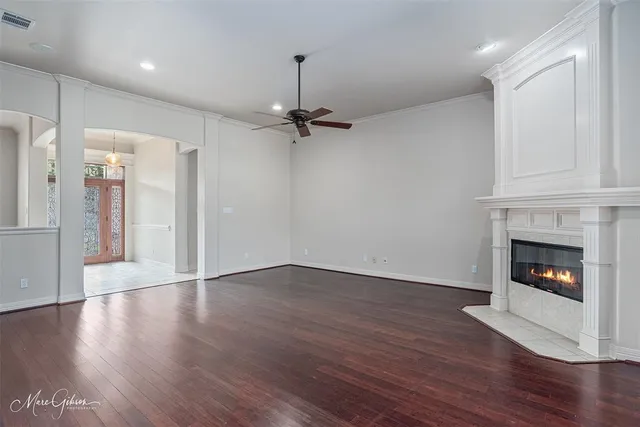 a view of a livingroom with a fireplace a ceiling fan and wooden floor