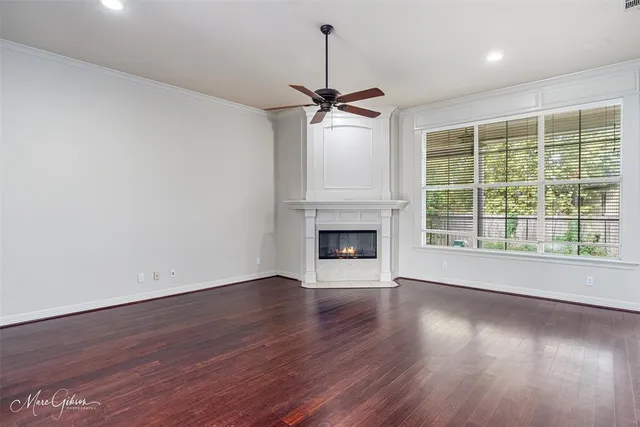 a view of an empty room with wooden floor fireplace and a window