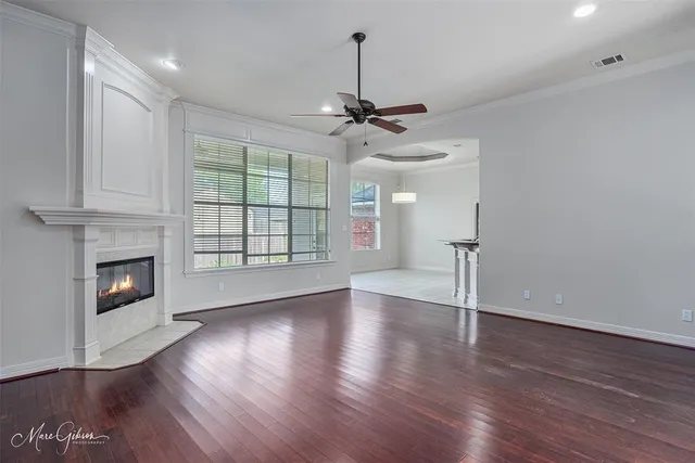 a view of an empty room with wooden floor fireplace and a window