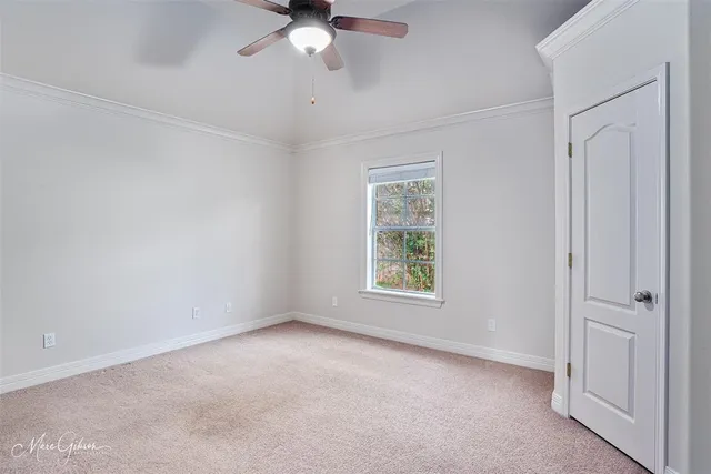 an empty room with a chandelier fan and windows